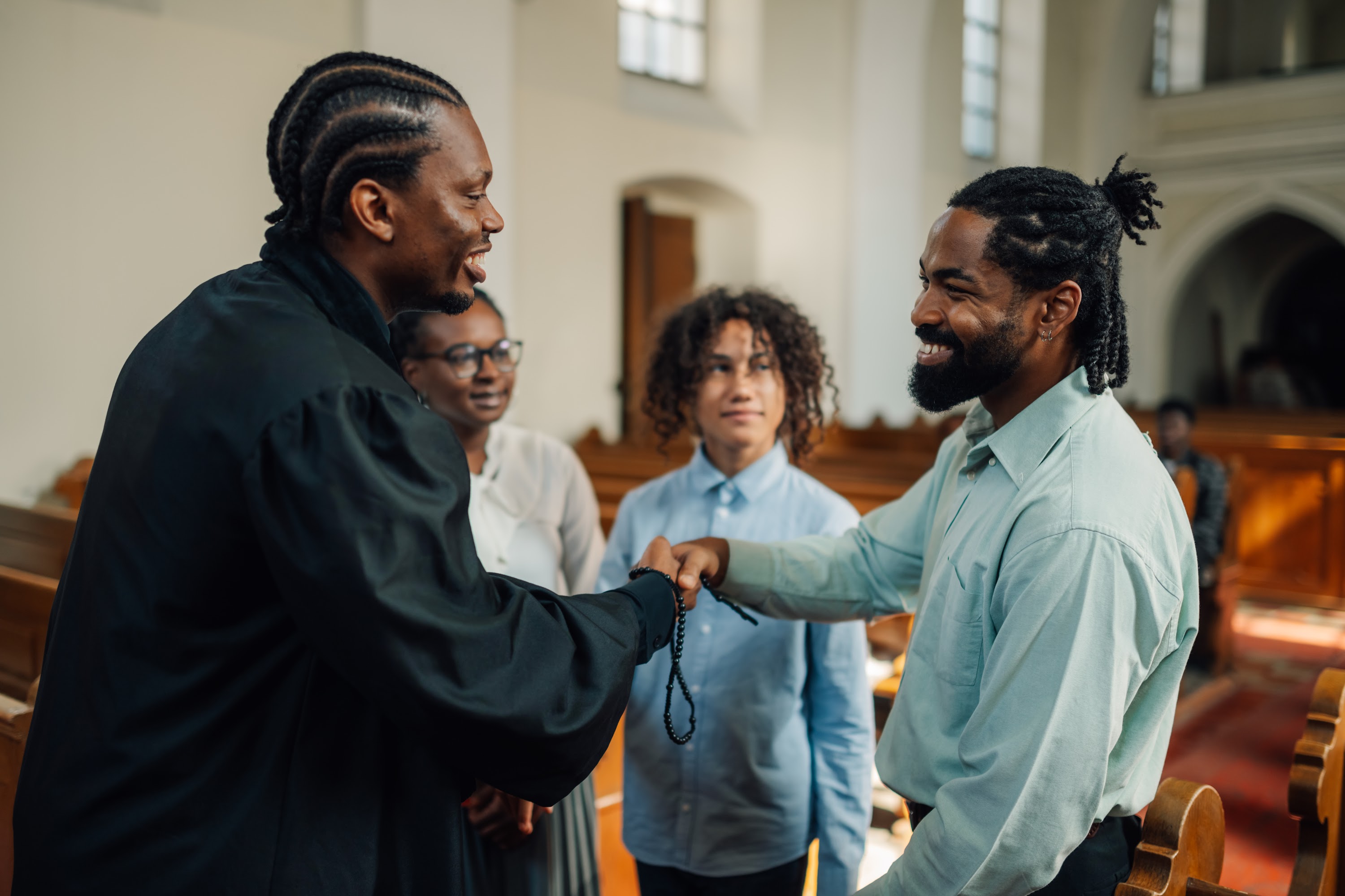 priest-giving-rosary-beads-to-young-man-in-church-2025-04-03-21-00-59-utc.jpg