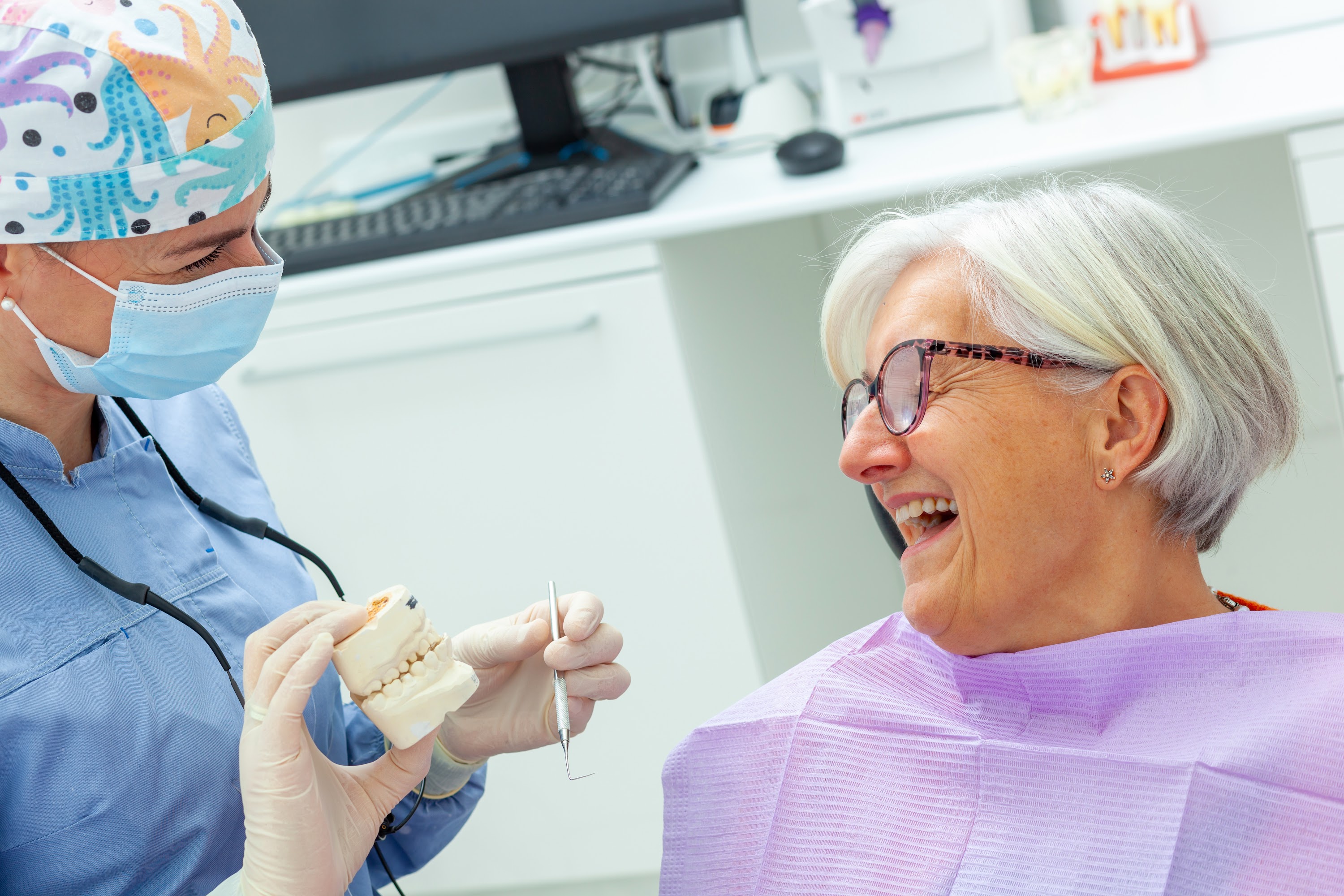 dentist-showing-denture-model-to-smiling-senior-wo-2025-03-23-22-00-32-utc.JPG