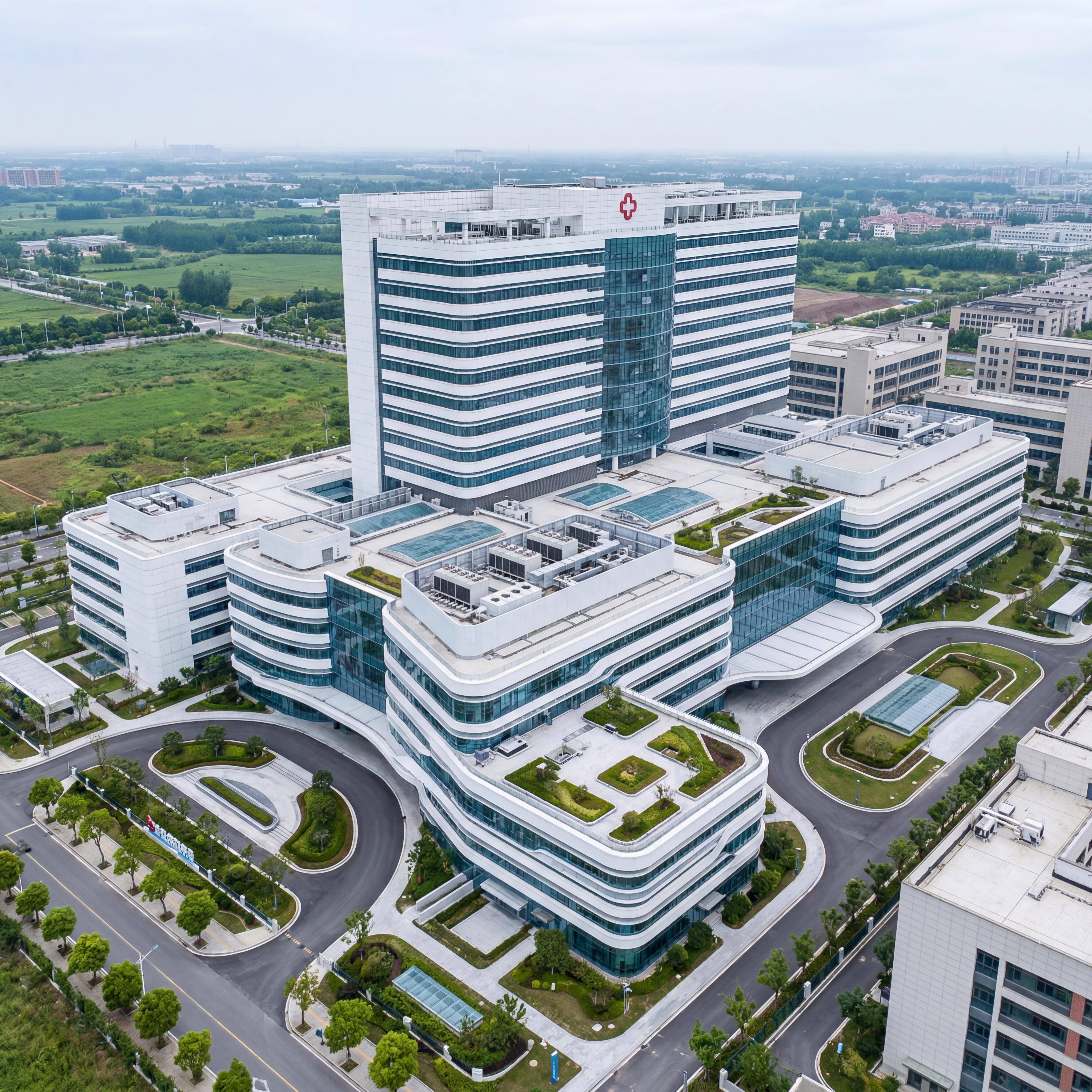 A large modern hospital complex viewed from a high aerial perspective, featuring a multi level white building with clean horizontal lines and curved glass facades. The architecture has a central tall medical tower with a red cross symbol on the rooftop, connected to lower wings forming an expansive healthcare campus. The design includes rooftop mechanical details, skylights, and geometric terraces surrounded by landscaped gardens, curved driveways, and tree lined pathways. Rendered in a photorealistic style with sharp focus and high detail, natural daylight evenly illuminates the structure under a soft overcast sky. The surrounding environment includes green fields, roads, and neighboring buildings creating a calm professional atmosphere, modern healthcare architecture, high resolution, detailed textures.