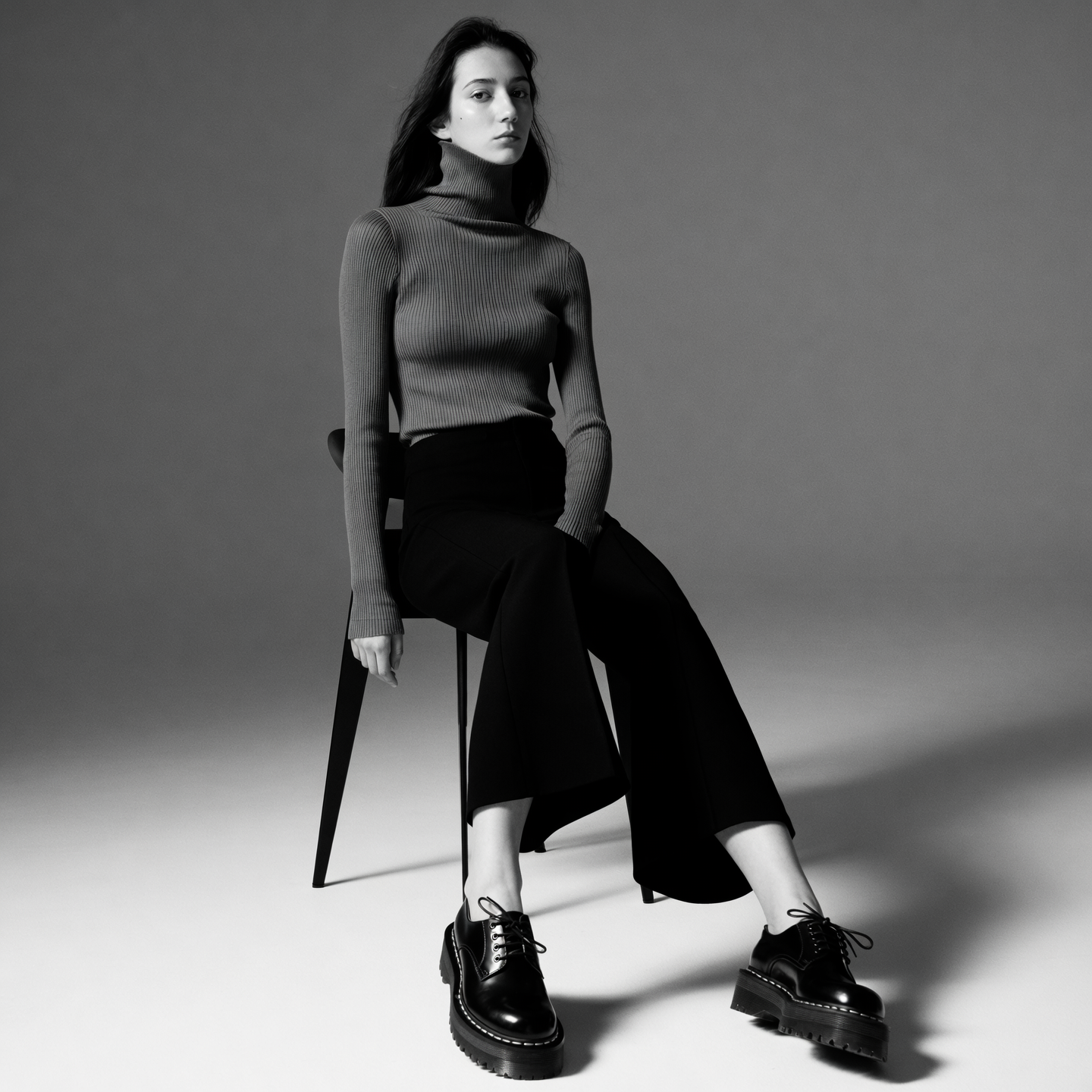 Monochrome outfit with rib-knit turtleneck, cropped wide-leg trousers, and lug-soled derby shoes styled with soft lighting.