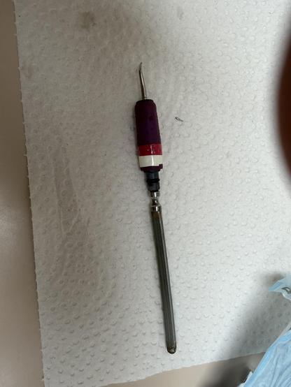 A cavitron ultrasonic dental instrument with a broken tip on a paper towel.