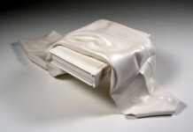 Hyper-realistic Wood carvings that look like flowing fabric A piece of white fabric lying ove a book, both carved on wood